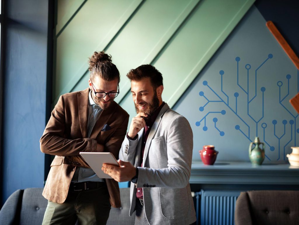 2 people smiling, looking at a tablet